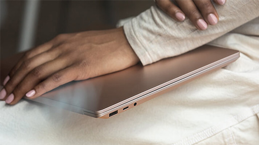 一位女性的膝盖上有一台合上的 Surface Laptop 3