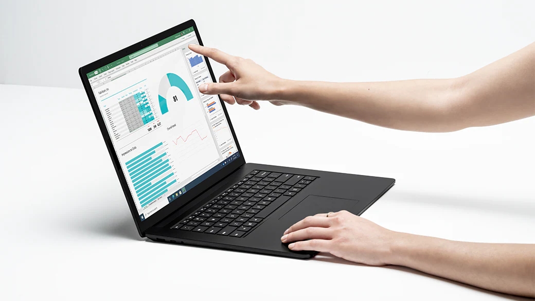 一个人在使用 Surface Laptop 4 工作，一只手在键盘上，另一只手在触摸显示屏。