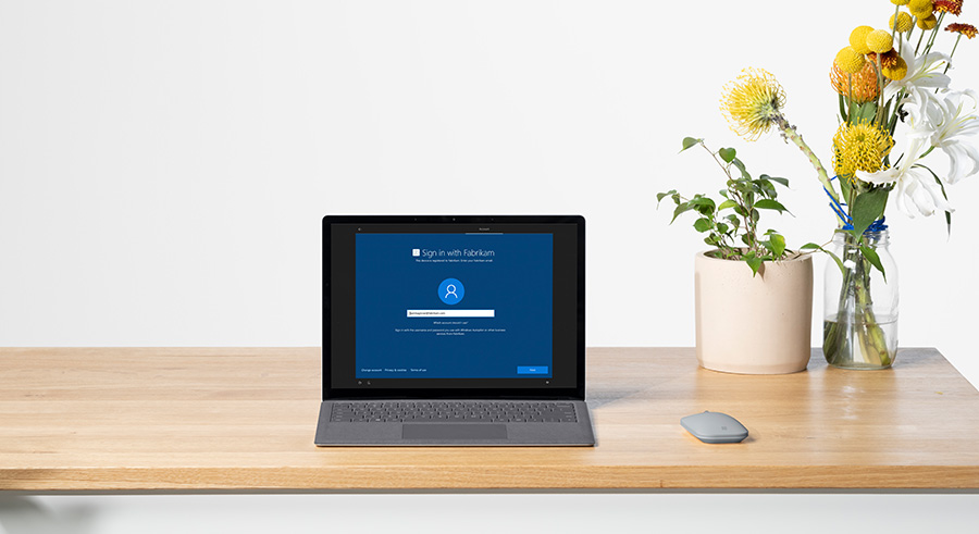 Surface Laptop 4 商用版置于桌上，旁边放着鼠标和两个花瓶。