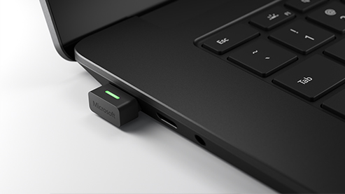 Microsoft Teams USB 适配器插入 Surface Laptop 4 设备接口的特写图 。