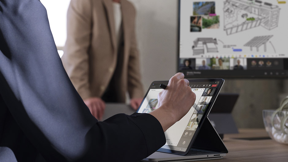 一个人正在 Surface 设备的屏幕上书写，与此同时，图像被投影到 Surface Hub 3 商用版上。