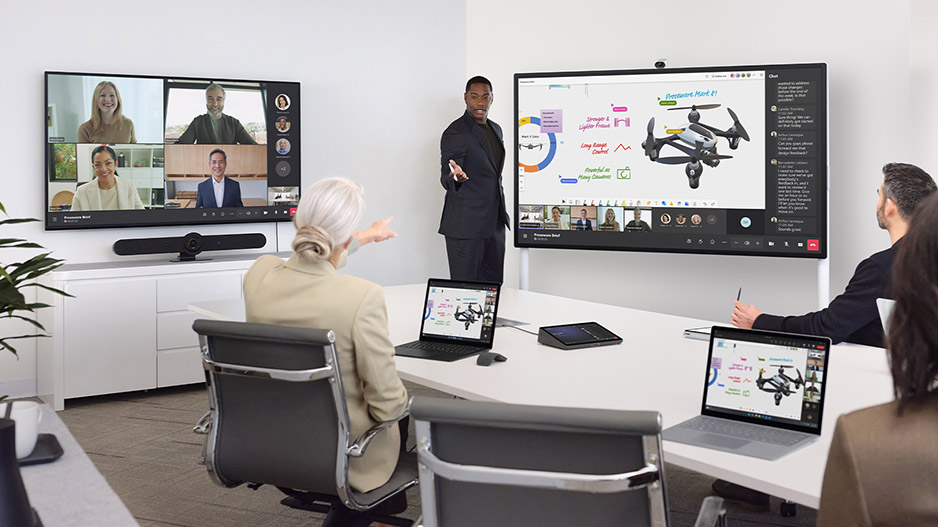 一个在 Surface Hub 3 商用版上使用白板功能的人，与在办公室办公和远程办公的团队成员协作。