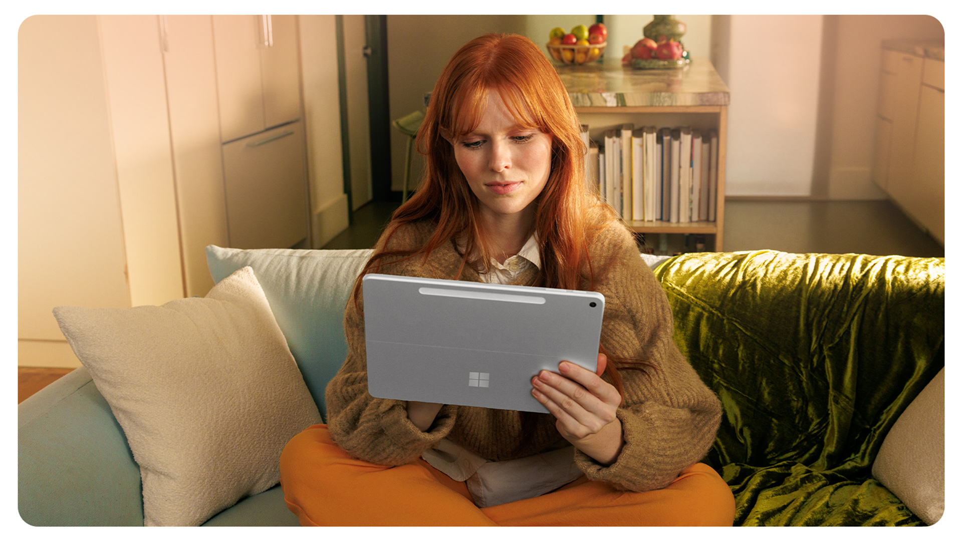 一个人坐在沙发上,手持一台 Surface Pro 商用版。