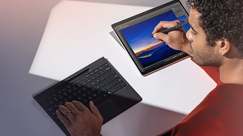 一位男性用户正在用Surface Pro商用版搭配外接的Surface Pro Flex键盘挥洒创意